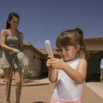 Mother and daughter checking temperature outside Apache Junction home on hot summer day