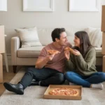 Couple eating pizza on floor while unpacking in their new Queen Creek apartment