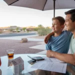 Father and son reviewing utility bill on patio at sunset in Laveen, AZ