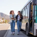 Two young women walking toward a Valley Metro bus on a suburban street corner in Buckeye, Arizona