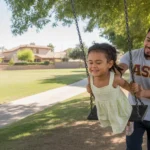 Father pushing his young daughter on a tree swing in a park in Glendale, Arizona