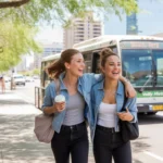 Two young women friends laughing and walking together to catch a city bus in Downtown Phoenix on a sunny day