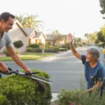 A man trims shrubs in front of his Spring Valley home while his neighbor tends her garden across the street.