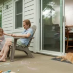 Family relaxing on shaded patio while cat sleeps by air vent indoors on a hot summer day in Concord, NC