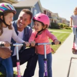 Father and young daughters sitting on front steps of suburban home, girls laughing and preparing to ride scooters on cul-de-sac