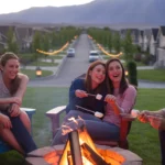 Four friends relax around a backyard firepit in Lehi, Utah on a summer evening, smartphones resting nearby.
