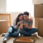 Couple eating pizza on floor of new apartment in Winter Garden surrounded by moving boxes