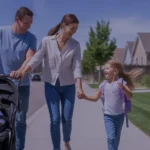 A young family happily walking together on a sunny sidewalk in Taylorsville, Utah.