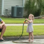 Father and daughter enjoying the lawn and water sprinkler on a hot summer day in Lakeland, Florida