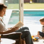 Father reads book in armchair by patio door to catch breeze and save on AC costs in Frisco, TX home